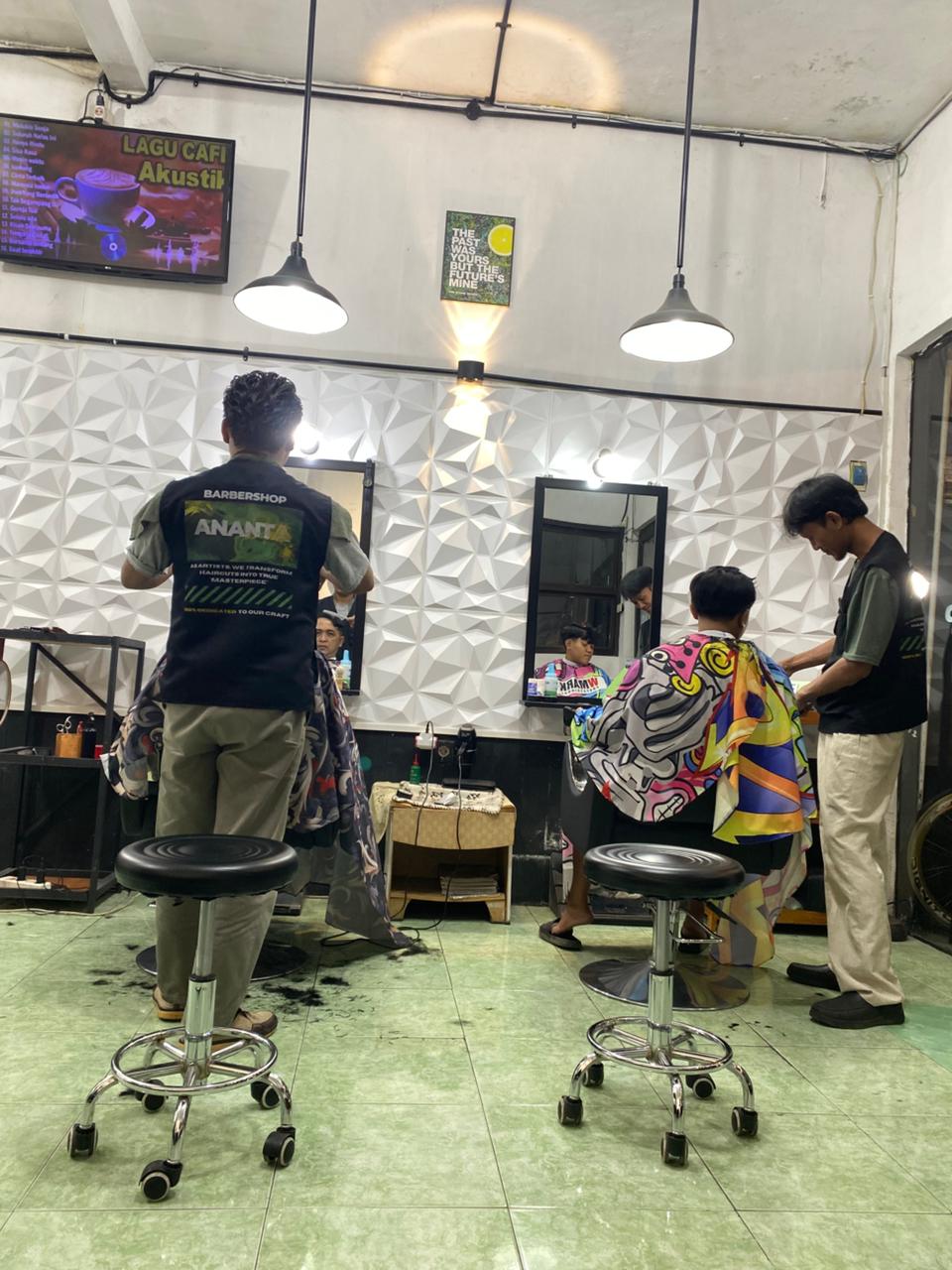Seorang barber profesional sedang memotong rambut klien di Ananta Barbershop
